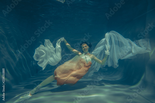 Fotografia elegant slender girl swims underwater like a free diver in a white evening dress