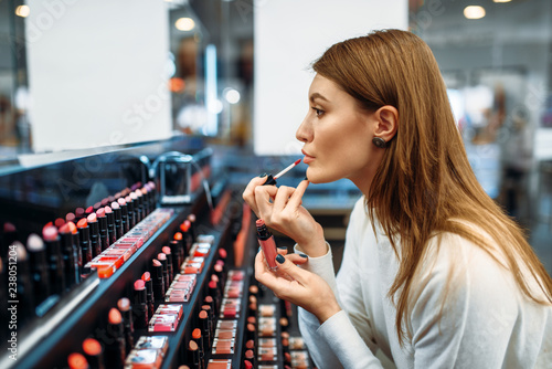 Female customer testing lip liner in make-up shop