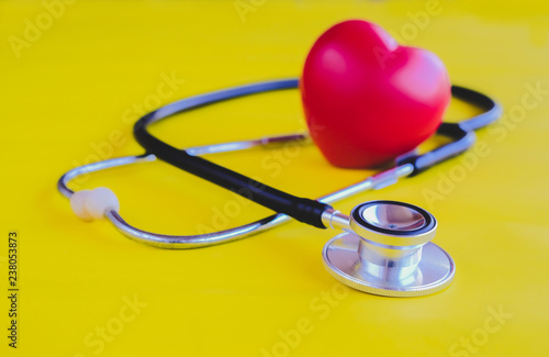 Stethoscope with red heart on yellow vintage background.