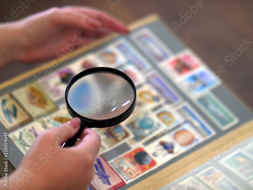magnifying glass in hand against the background of an album with postage stamps