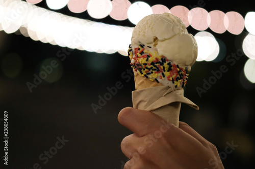 Hand holding vanilla ice cream in night