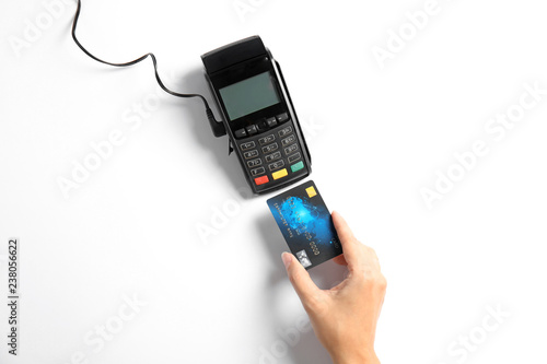 Woman using modern payment terminal on white background, top view