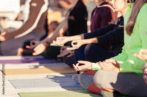 Close up hands of yoga group sit and meditates outdoor on fitness terrace   alm and relax concept  wellness and healthy lifestyle. People sitting in lotus position on yoga mat  Jnana Mudra