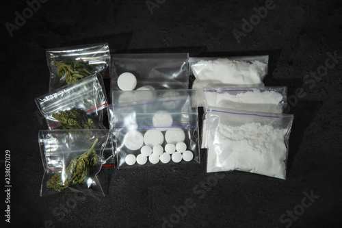 Fotografie Cocaine, dried hemp and ecstasy on dark table, top view