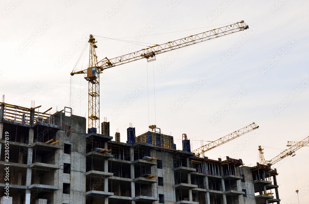 Construction of a high-rise building with a crane. Building construction using formwork. The construction crane and the building against the blue sky. Construction of a high-rise building with a crane. Building construction using formwork. The construction crane and the building against the blue sky.