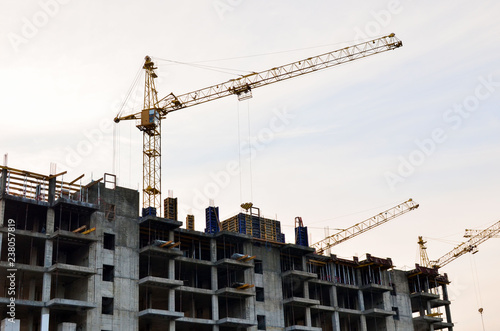 Construction of a high-rise building with a crane. Building construction using formwork. The construction crane and the building against the blue sky.