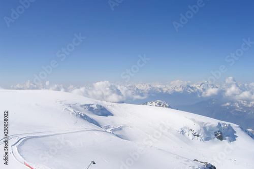 a long ski slope from the very top of the mountain; a deep gorge, blue haze; the Swiss Alps