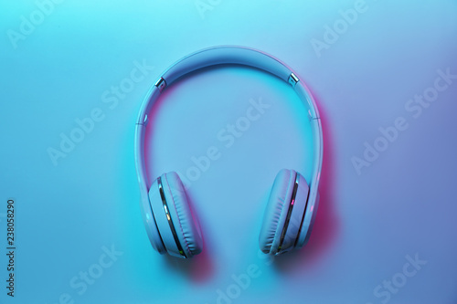 Stylish modern headphones with earmuffs on color background, top view