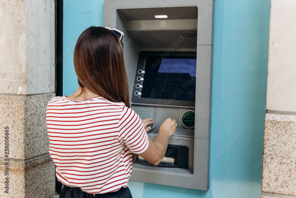 A young woman takes money from an ATM. Finance, credit card, withdrawal of money. Life style. Grabs a card from the ATM. A young woman takes money from an ATM. Finance, credit card, withdrawal of money. Life style. Grabs a card from the ATM.