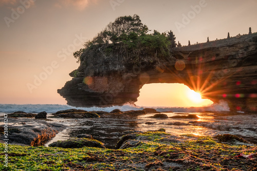 Sunshine through of rocky cliff on seashore at sunset