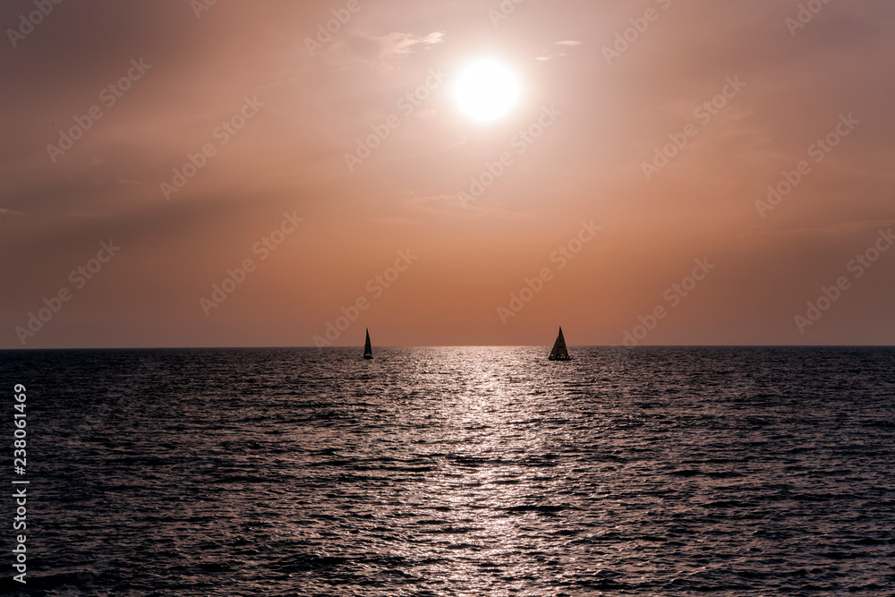 Two sailing boats at sunset in orange tones over the Mediterranean sea in Tel Aviv, Israel