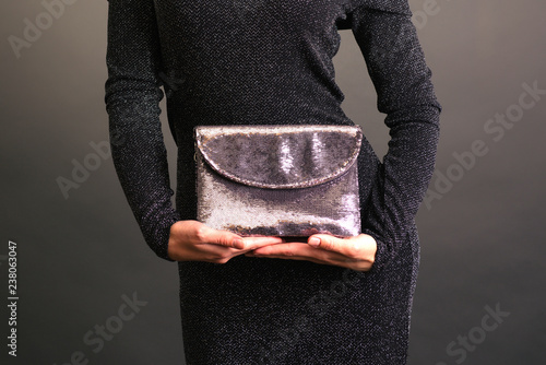 Young woman holding a shining clutch isolated on background