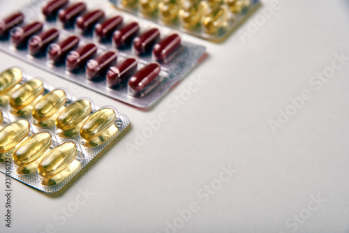 Two packs of yellow translucent tablets and one pack of maroon vitamins in capsule tablets. Several different packages of drugs, medicines, vitamins, minerals, nutritional supplements.