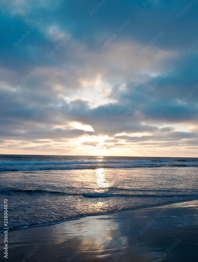 The sun setting into the Pacific ocean seen from a beach in southern California, USA