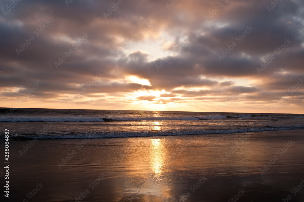 The sun setting into the Pacific ocean seen from a beach in southern California, USA