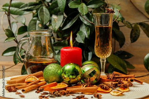 Holiday Christmas decoration with white wine  Christmas ball  candle  dried orange  anise stars and sticks of cinnamon. Wooden table and vintage background.