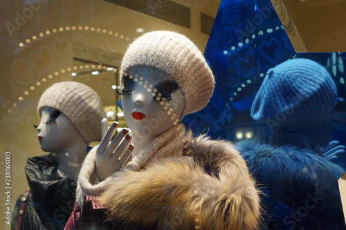 Mannequin with long eyelashes, red lips and red nail in white knitted hat