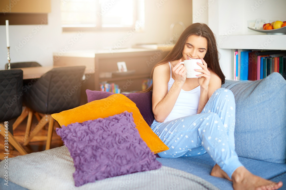 Beautiful young woman relaxing on sofa at home early morning and drinking tea Beautiful young woman relaxing on sofa at home early morning and drinking tea