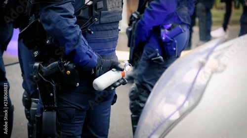 French Police officers securing the zone in front of the yellow vests movement protesters on Quai des Bateliers street woman officer with tear gas bottle ready to use it 