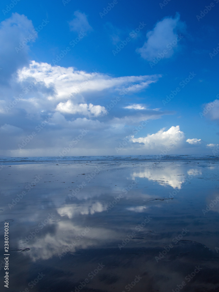 Beautiful cloud and blue sky reflections at Westward Ho! beach in the wet sand