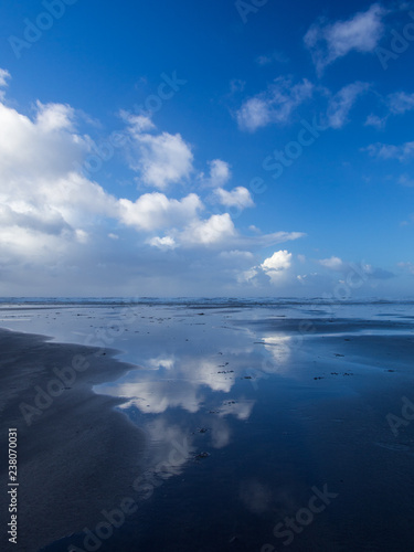 Beautiful cloud and blue sky reflections at Westward Ho! beach in the wet sand