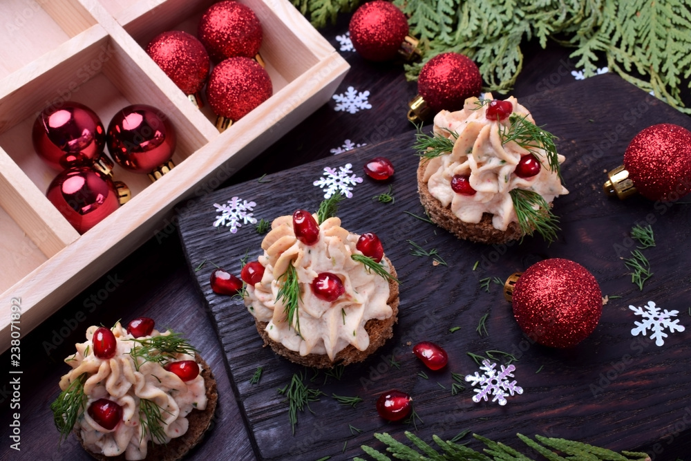 Canape shaped as a Christmas tree with pate garnished with pomegranate and dill surrounded by Christmas decorations Canape shaped as a Christmas tree with pate garnished with pomegranate and dill surrounded by Christmas decorations