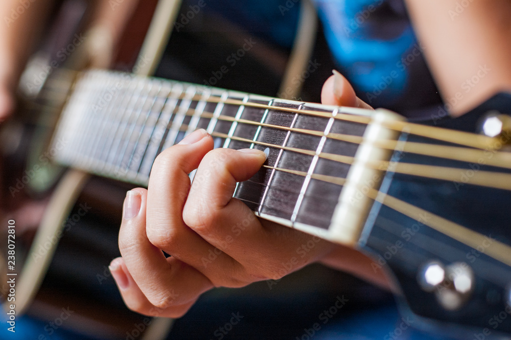 Closeup of young woman hand playing on black acoustic guitar Closeup of young woman hand playing on black acoustic guitar
