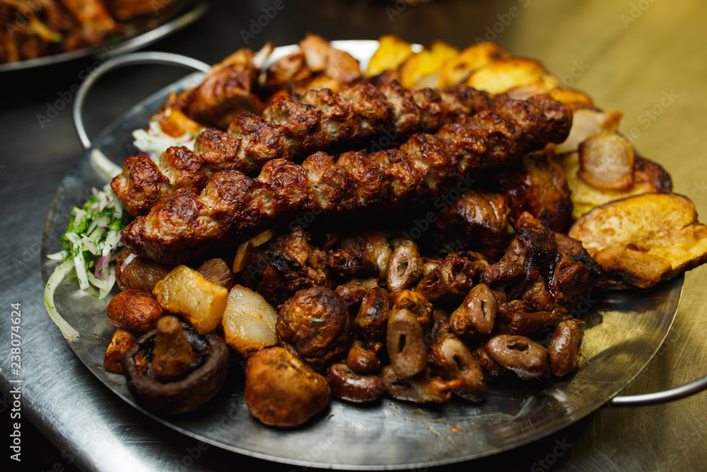 Lula kebab with vegetables. Minced mutton chop on the big steel plate Lula kebab with vegetables. Minced mutton chop on the big steel plate