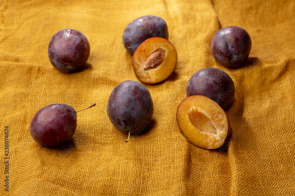 Fototapeta premium Fresh plums on yellow fabric