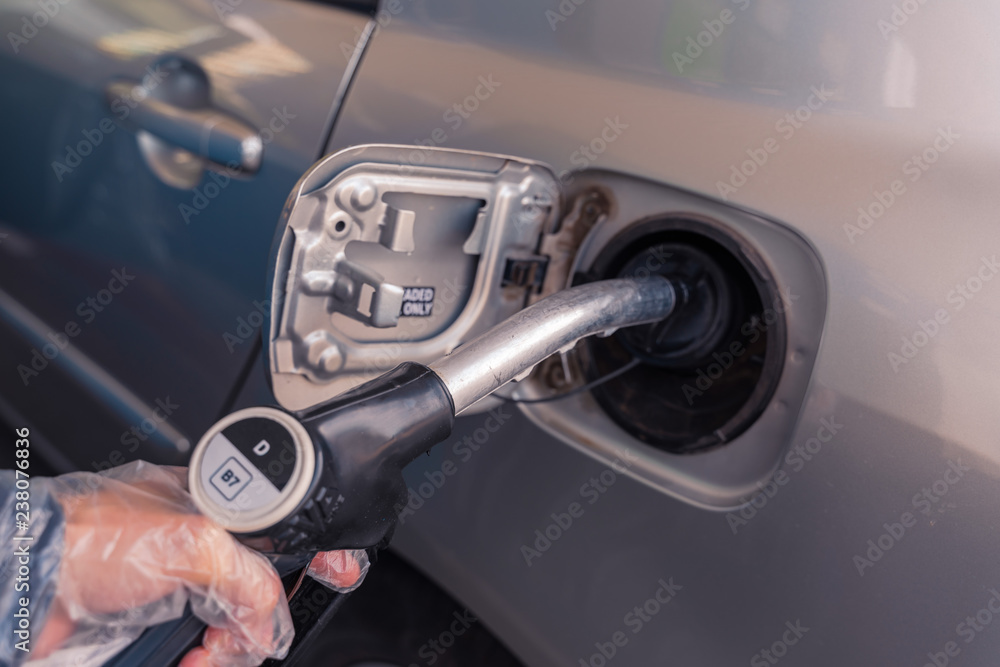 ..Fuel pistols at european Petrol station. Woman's hand  putting Diesel B7 fuel  black pistol to the fuel tank. Focus on the pistol, DD sign out of the focus.