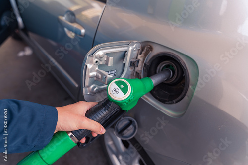 Fuel pistols at European Petrol station. Woman's hand  putting 95 E5 fuel  green pistol to the fuel tank. Focus on the pistol.