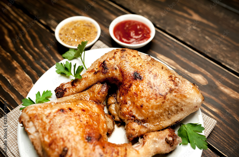 Chicken legs in a plate with mustard and ketchup on a wooden background. Chicken legs in a plate with mustard and ketchup on a wooden background.