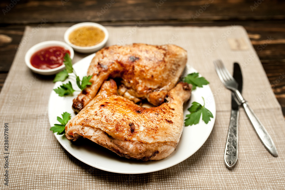 Chicken legs in a plate with mustard and ketchup on a wooden background.