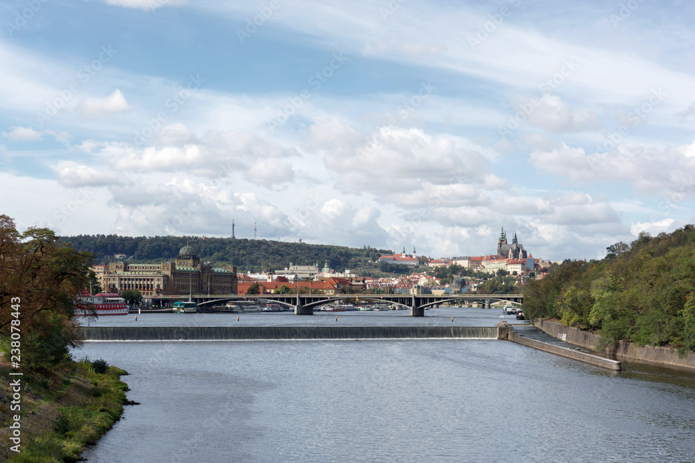 Prague panorama with Stefanik bridge, Vltava river, colorful rooftops, Petrin tower, Prague Castle and St. Vitus Cathedral in the distance, on a cloudy summer day