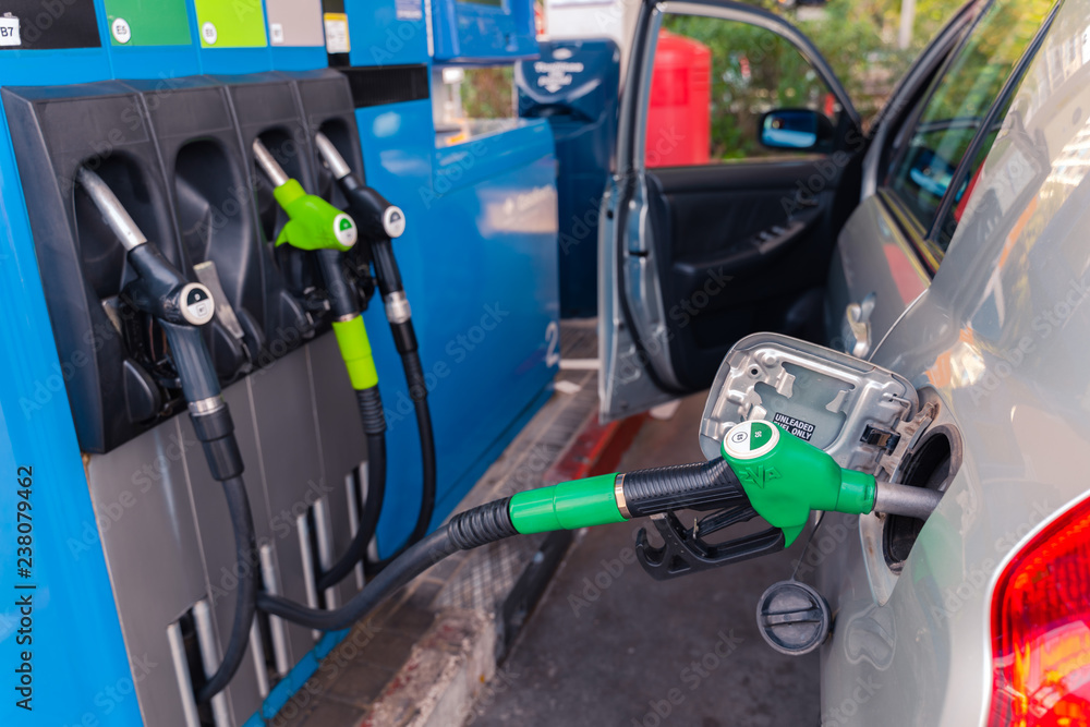 Fuel pistols at european Petrol station.  95 E5 fuel  green pistol inserted to the fuel tank of the car. Focus on the pistol.