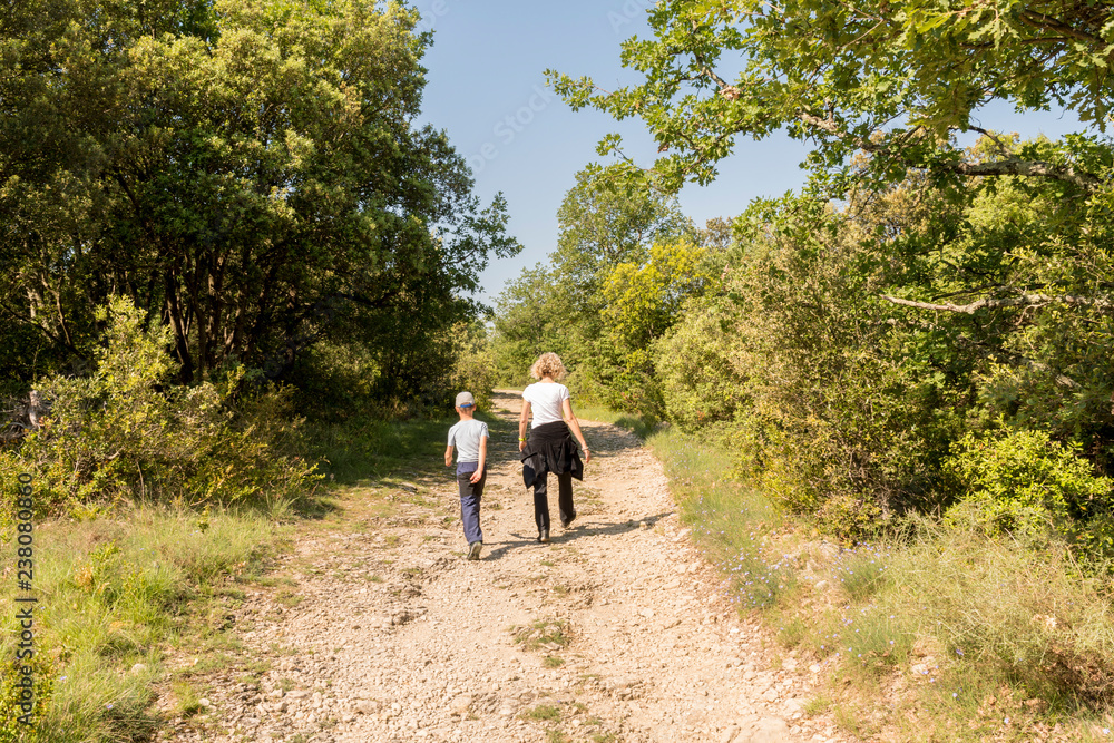 Mum and son hiking on a stone path in the wildness Mum and son hiking on a stone path in the wildness
