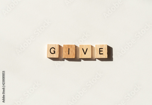 The word GIVE spelled in wooden letter tiles flat lay on white.