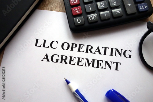 LLC operating agreement, pen, glasses and calculator on   desk photo
