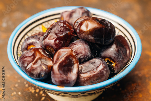 Dried dates in an oriental ceramic bowl on a dark background. Ramadan snacks