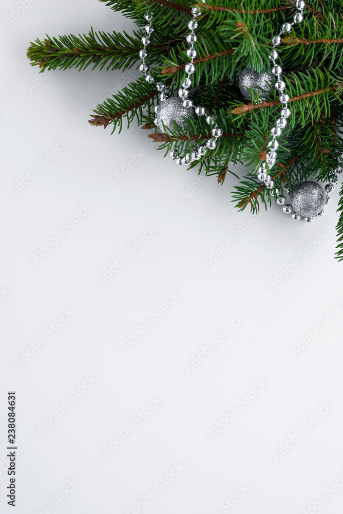 Festive vertical greeting card with copy space for your wishes. Christmas decorations: green conifer tree branches, little silver baubles and chain. Festive vertical greeting card with copy space for your wishes. Christmas decorations: green conifer tree branches, little silver baubles and chain.
