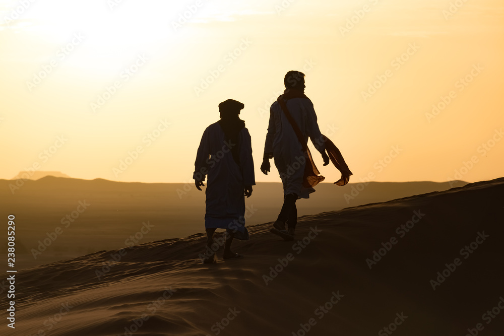 Silhouette of Berber and camel at bloody red sunset, Merzouga in Morocco, Sahara Desert, North Africa.