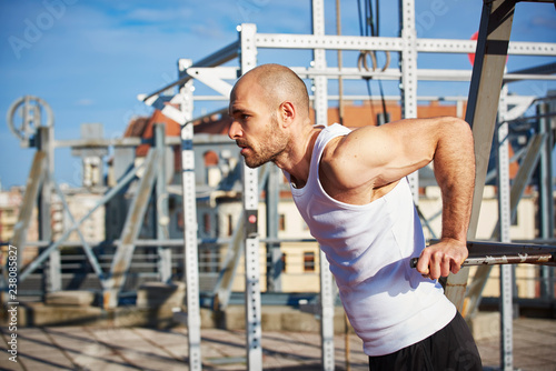 Man doing pull ups training while workout on the street