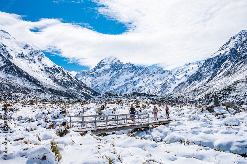 2018, Oct 13 - New Zealand, Mount Cook Natioanl Park, People walking on the boardwalk in Hooker Valley track. Winter snow after a snowy day.