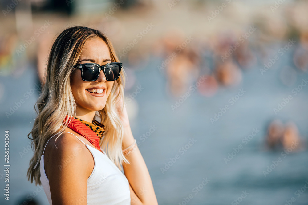 Smiling woman with sunglasses standing at the Beach