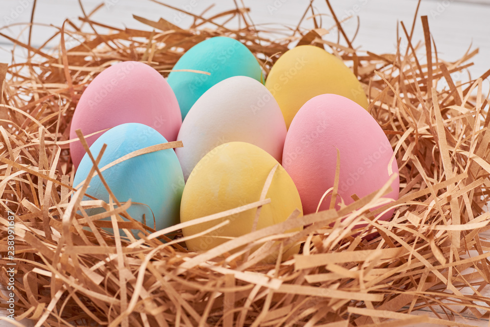 Easter background. Colorful easter eggs in paper nest on a white background, close up Easter background. Colorful easter eggs in paper nest on a white background, close up