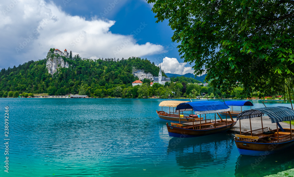Fototapeta premium Boats at the pier that help one to trip to the island in the middle of the Bled lake and ringing the bell of the 17th century church. Slovenia.