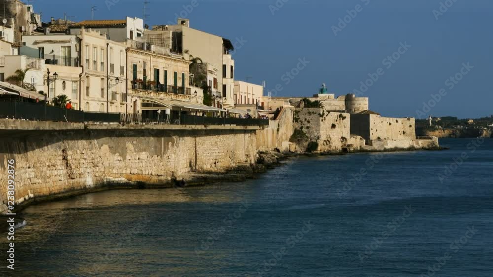Syracuse,Ortygia, Sicily, Italy.People walking on the Lungomare Alfeo. In the background is the Castello Manace Syracuse,Ortygia, Sicily, Italy.People walking on the Lungomare Alfeo. In the background is the Castello Manace