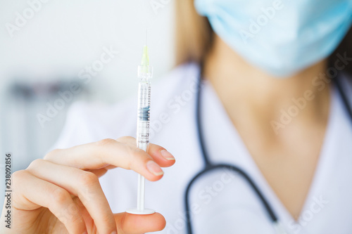 Female doctor or physician holding hypodermic syringe with injection