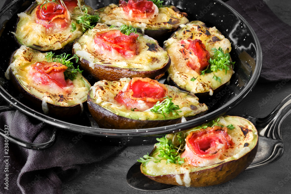 Keto diet dish: Avocado Boats with crunchy bacon, melted cheese and cress sprouts on dark