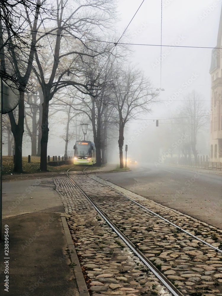 Modern tram on an old street in Riga on a foggy autumn morning. Latvia